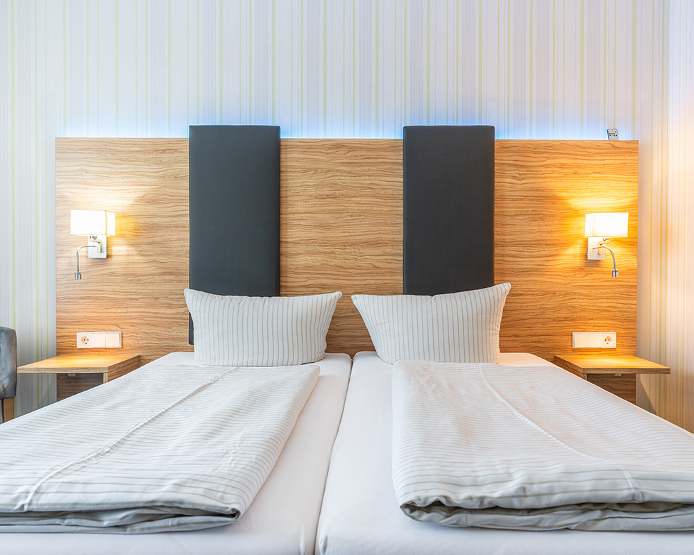 Zwei Betten mit Holzkopfteil und Leselampen in einem Hotelzimmer